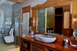 a bathroom with a sink and a toilet and a mirror at Kenran Resort Ubud By Soscomma in Ubud