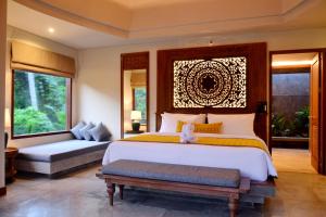a bedroom with a large bed and a bench in it at Kenran Resort Ubud By Soscomma in Ubud