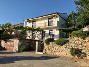 a large white house with a stone wall at Apartment Tušek in Jadranovo