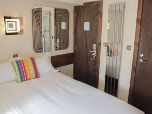 1 dormitorio con cama blanca y puerta de madera en Guest And The City, en Brighton & Hove