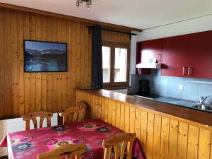 a kitchen with a table and chairs and a kitchen with red cabinets at Melezes K SKI LIFT & NATURE apartments by Alpvision Résidences in Veysonnaz