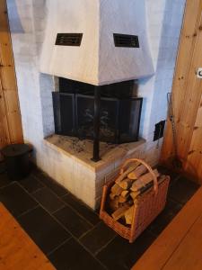 a stone fireplace with a basket of fire wood at Sjöstuga Vätö in Harg