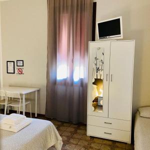 a bedroom with a white cabinet with a television on top at Low Cost Ferrara in Ferrara