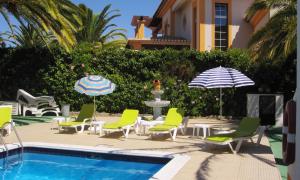 a pool with chairs and umbrellas next to a house at Palm Villa Estudios in Lagos