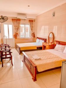a bedroom with two beds and a table and chairs at Thien Nhan Hotel in Cửa Lô