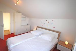 キュールングスボルンにあるBuesumer-Ring-Strandmuschel-501のベッドルーム1室(白いベッド1台、壁に蝶が飾られたベッド1台付)