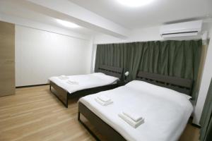 two beds in a hotel room with white sheets at Uhome千駄木静雅民宿旅馆 in Tokyo