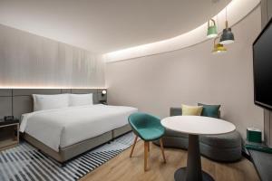 a hotel room with a bed and a table at Holiday Inn Shanghai Nanjing Road by IHG in Shanghai