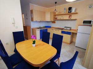 a kitchen with a wooden table and blue chairs at Apartment Mirna in Baška