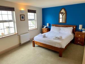 a bedroom with a large bed with a blue wall at La Ville Hotel in Alderney