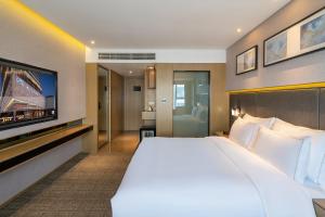 um quarto de hotel com uma cama grande e uma televisão de ecrã plano em Zenith Hotel-Near Train Station & The Mixc em Xiamen