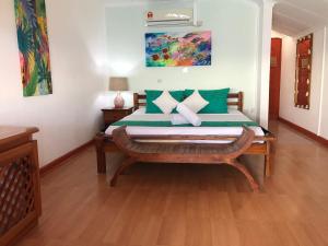 Schlafzimmer mit einem Bett mit grünen und weißen Kissen in der Unterkunft Hotel L'Ocean in La Digue