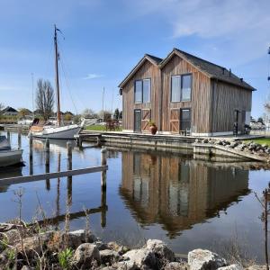 a wooden house on a dock next to a body of water at Roggebroek 13 in Stavoren