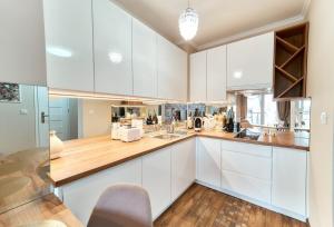 a kitchen with white cabinets and a wooden counter top at LAGUNA Apartament Polanica Residence 11 in Polanica-Zdrój
