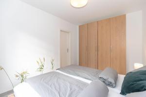 キュールングスボルンにあるHaus-Ostseewelle-Wohnung-3-9527の白いベッドルーム(ベッド1台、木製キャビネット付)