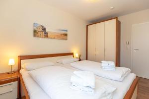 キュールングスボルンにあるBuesumer-Ring-Morgensonne-9395の白いシーツとタオルが備わるベッドルームのベッド2台