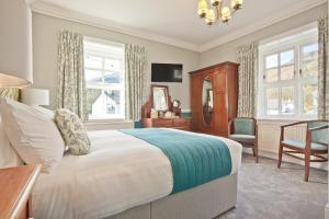 a bedroom with a bed and a chair and windows at The Yewdale Inn and Hotel Coniston Village in Coniston