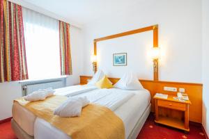 a hotel room with two beds and a mirror at Hotel Germania Gastein - ganzjährig inklusive Alpentherme Gastein in Bad Hofgastein