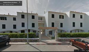 un gran edificio blanco con un coche aparcado en un aparcamiento en Apartamento Saura, en Cala en Blanes