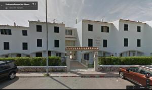a large white building with a car parked in a parking lot at Apartamentos Saura in Cala en Blanes