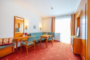 a hotel room with a couch and a table and a television at Hotel Germania Gastein - ganzjährig inklusive Alpentherme Gastein in Bad Hofgastein