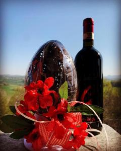 a bottle of wine and a red flower in a vase at Enoagriturismo L' Acino d'Uva in Cunico