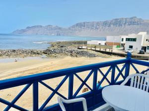balcón con mesa y sillas y playa en Mirador del Risco de Famara, en Famara