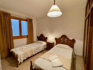 a bedroom with two beds and a pendant light at Ca Blai de Brull en el centro de Tivissa in Tivissa