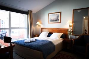 a bedroom with a bed with a blue blanket and a window at Hotel Møllehuset in Hadsund