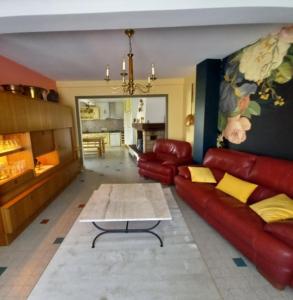 sala de estar con sofá de cuero rojo y mesa en chez cadet, en Larzicourt