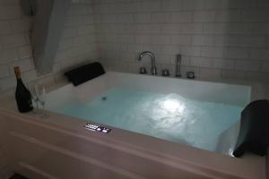 una vasca da bagno bianca con una bottiglia di vino e un bicchiere di Appartement jacuzzi privatif : Urban Love a Verneuil d'Avre et d'Iton