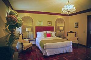 1 Schlafzimmer mit einem Bett, 2 Stühlen und einem Kronleuchter in der Unterkunft Terrazas de Golf Boutique Hotel in San José