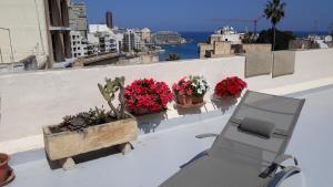 a chair and flowers on a wall with a view at Balluta Hill House in Sliema +36 photos
