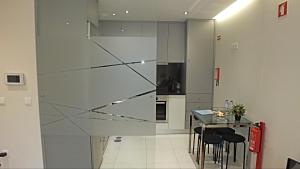 uma cozinha com uma divisória de vidro com uma mesa e cadeiras em Valadim Flats no Porto