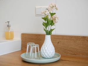 a white vase with flowers on a plate on a table at Ferienhaus Dorfleben in Vogtsburg
