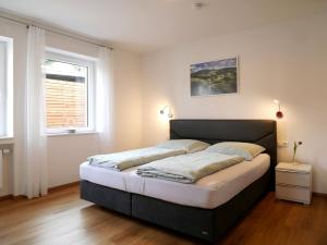 Un dormitorio con una cama grande con dos ventanas. en Ferienhaus Dorfleben, en Vogtsburg