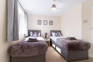 a bedroom with two beds and a window at Jupiter House by TJ Serviced Property in Peterborough