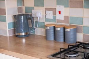 a counter top with a coffee pot and three cups at Jupiter House by TJ Serviced Property in Peterborough