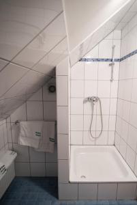 een wit betegelde badkamer met een douche en een bad bij Angelis Pension in Kelsterbach