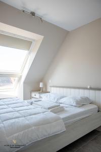 a bedroom with a large white bed with a skylight at Spacious apartment in the heart of Ostend near the sea in Ostend