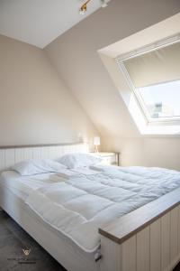 a bedroom with a large white bed with a skylight at Spacious apartment in the heart of Ostend near the sea in Ostend