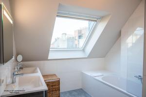 a white bathroom with a sink and a window at Spacious apartment in the heart of Ostend near the sea in Ostend