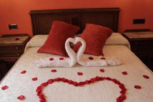Una cama con dos cisnes hechos para parecer corazones en Hotel Apartamentos Melihah en Daroca