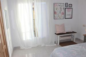 1 dormitorio con cortinas blancas, 1 cama y 1 mesa en Acogedor apartamento VALLE DEL JERTE, en Piornal