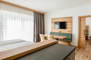 a bedroom with a bed and a desk and a tv at Kopeindlgut Apartments in Wals