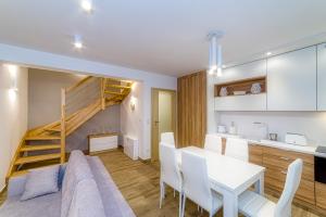 salon i kuchnia z białym stołem i krzesłami w obiekcie APARTAMENTY NA SKARPIE w mieście Szczawnica