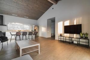 een woonkamer met een tv en een tafel en stoelen bij Prieka Villa in Sigulda