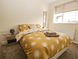 sypialnia z dużym złotym łóżkiem z oknem w obiekcie The Croft Bungalow w mieście Wigton