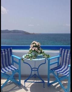 two chairs and a table with flowers on a balcony at Hotel Posidonion in Koufonisia
