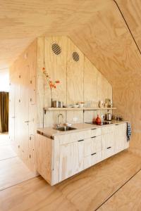 een keuken met houten kasten en een wastafel in de kamer bij Wikkelhuis 12 in Stavoren
